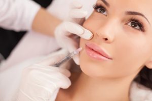 Close up of hands of cosmetologist making botox injection in female lips