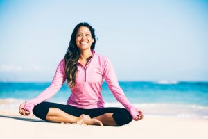 woman practicing yoga on the beach