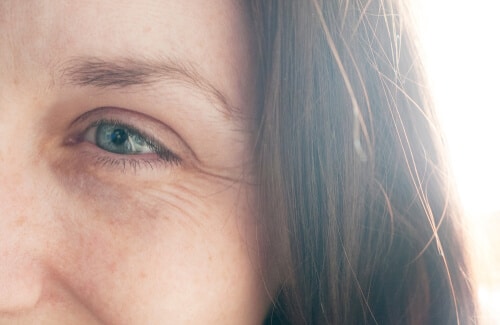 smiling woman with no make up blue eyes brown hair and freckles.showing crows feet around the eyes-img-blog