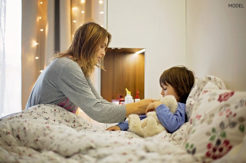 mother taking care of her sick, recovering kid in bed.