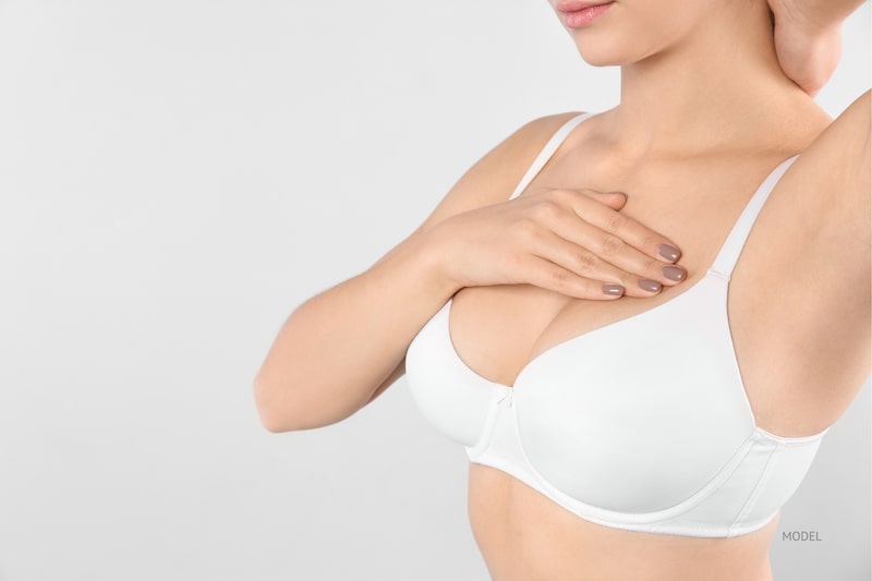 Woman feeling top of breast over a white bra