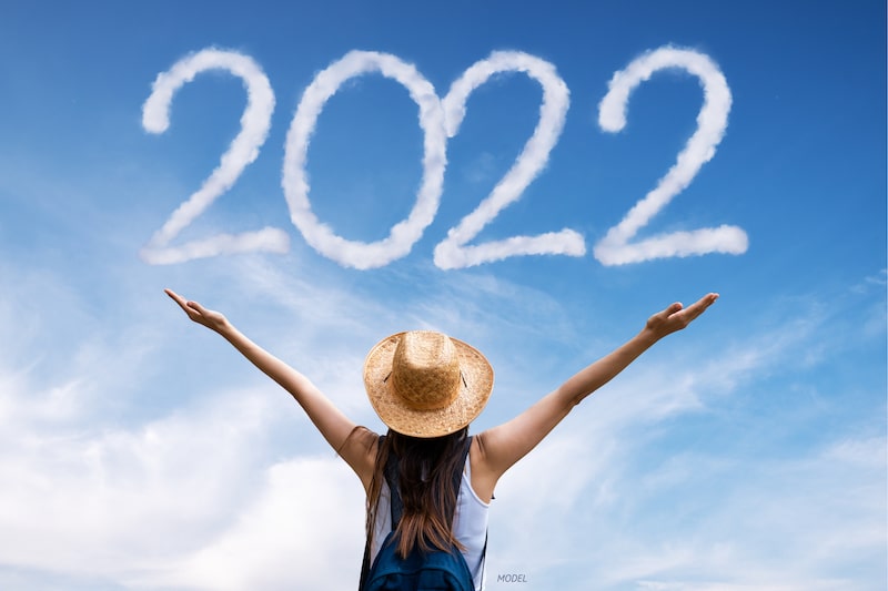 Woman stretching her arms to the sky, which reads 2022