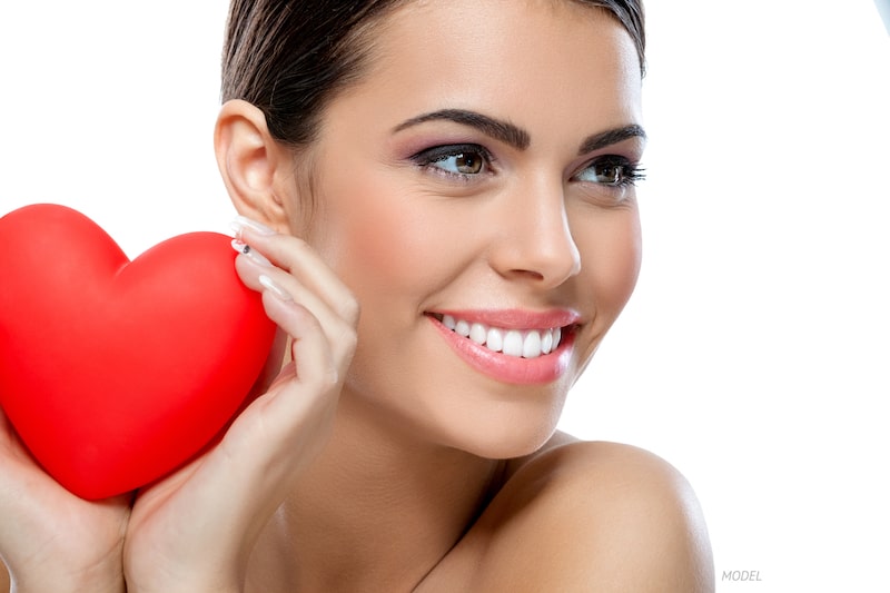 Happy, youthful woman holding a red heart.
