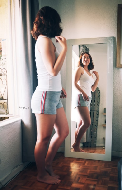 Woman looking at herself in a full-body mirror