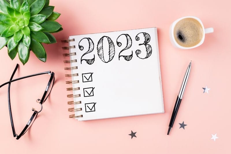 Pad of paper with a 2023 checklist on it sitting on a pink background