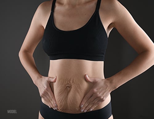 woman holding stomach with both hands